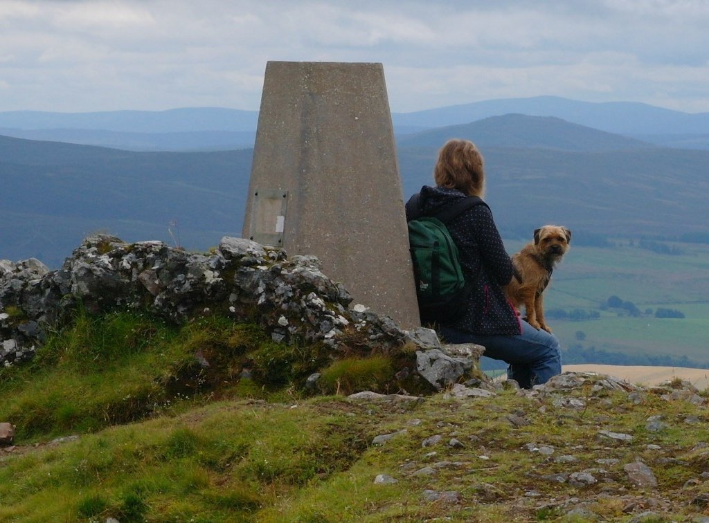 Ordnance Survey triangulation point beside a chunk of vitrified wall on the Tap o Noth. Border terrier monitors his master in this slightly spooky place.